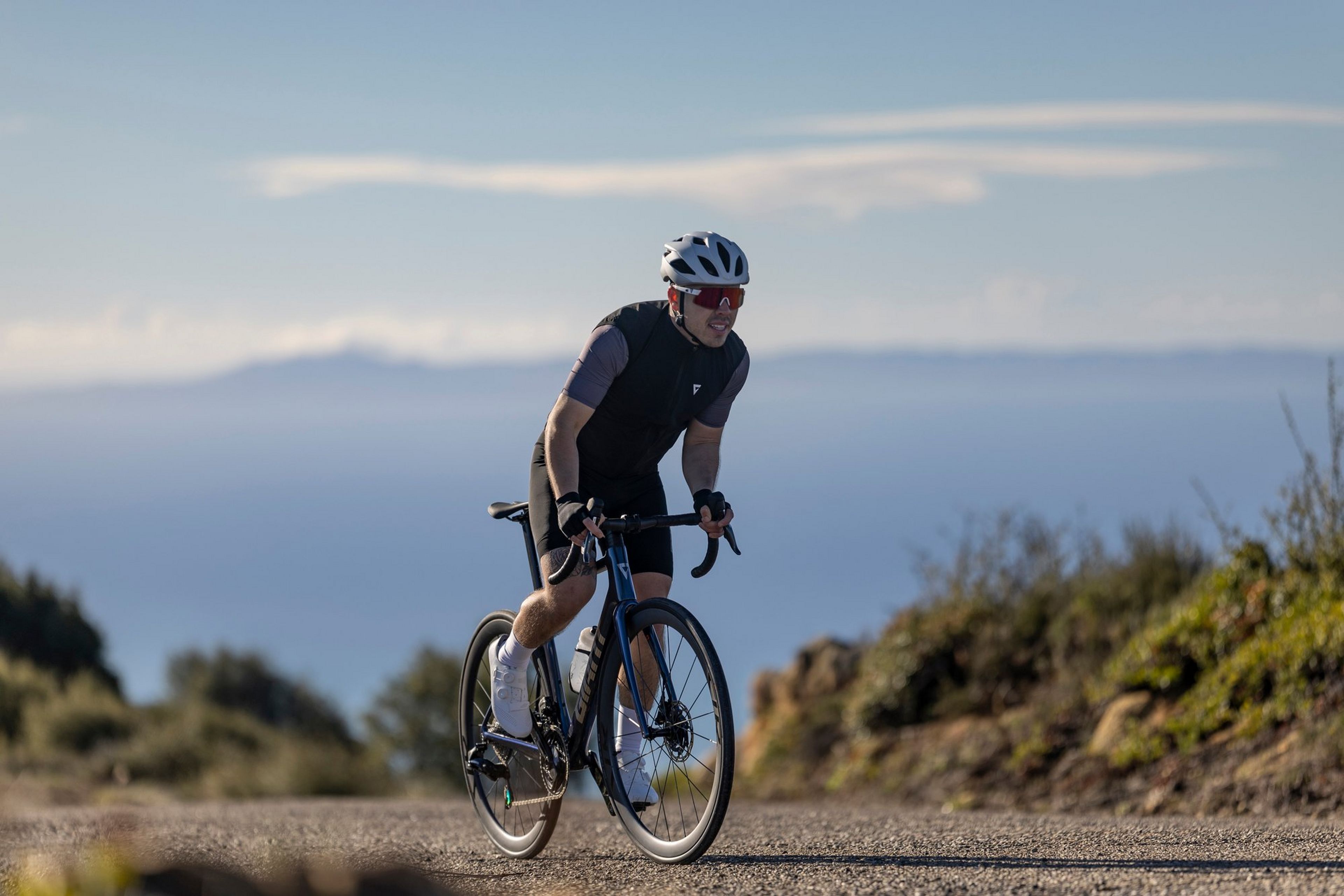 a man riding a bike on a road with mountains in the background