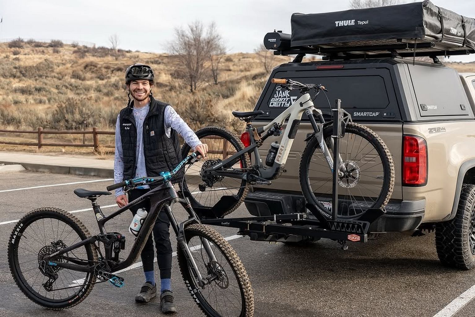 a man standing next to a truck with two bikes on the back